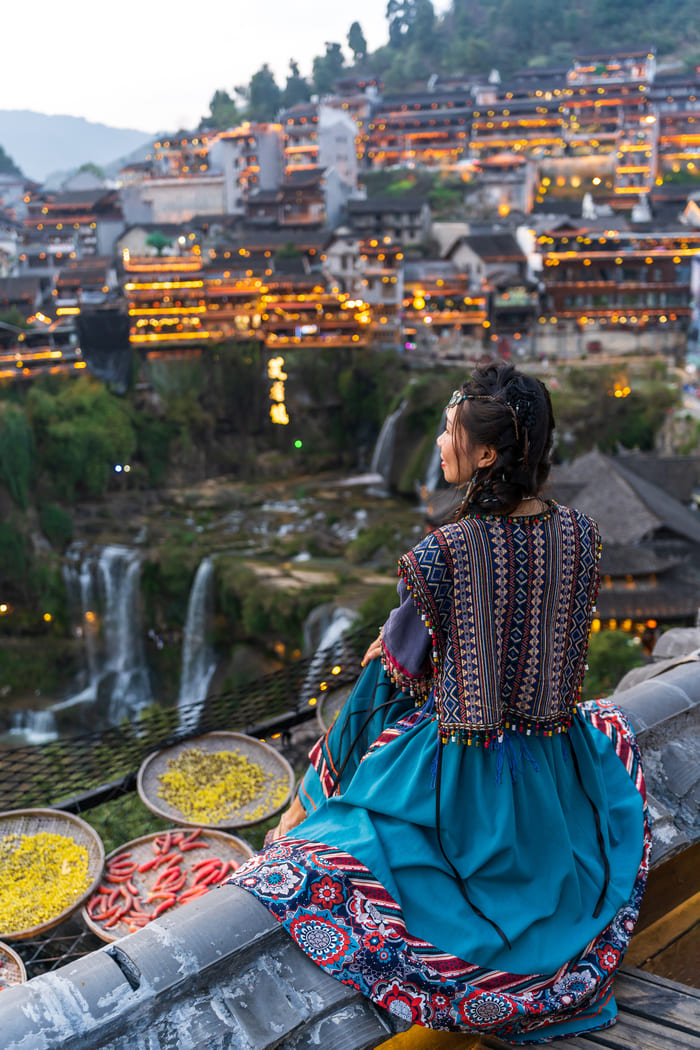 Mujer sentada y al fondo la ciudad lijiang